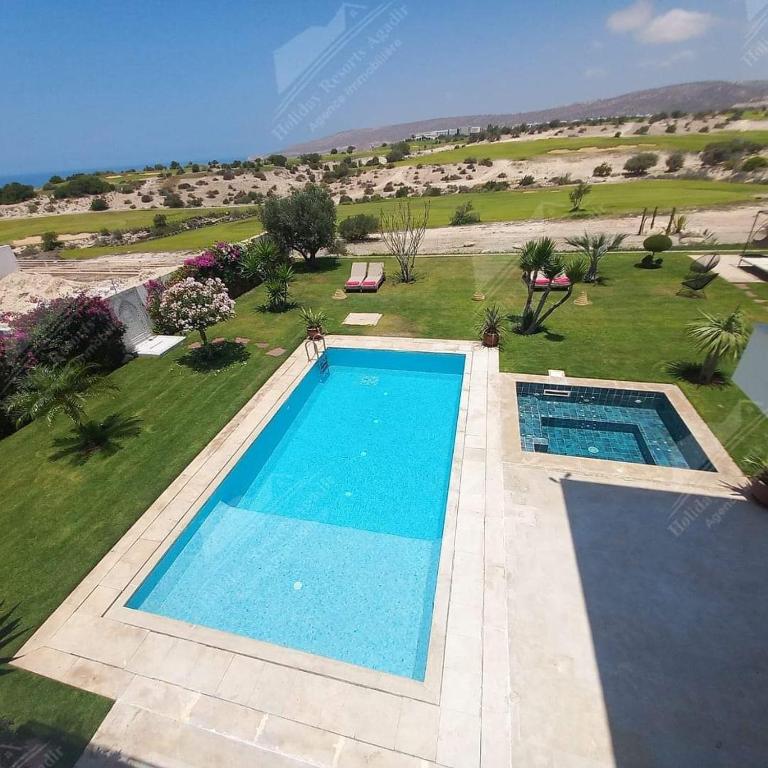 een uitzicht over een zwembad in een grasveld bij Sea Breeze Villa Taghazout Bay Amda golf & ocean view in Tamraght Ouzdar