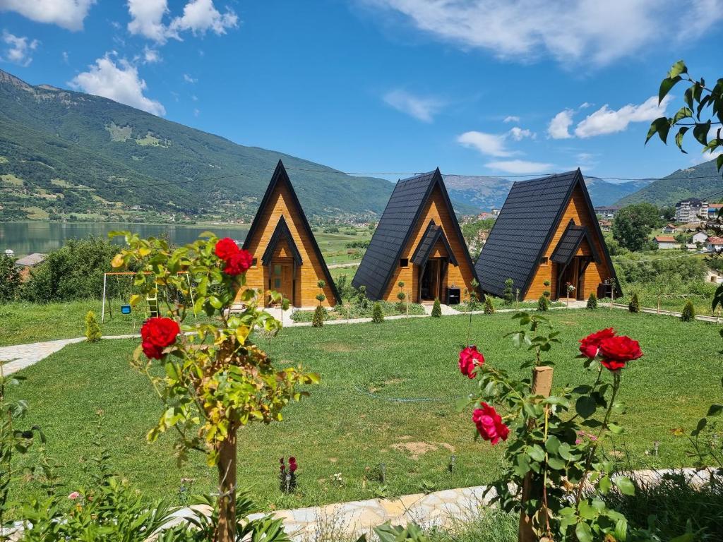 a row of wooden cabins on a field with flowers at Eka's Village in Plav