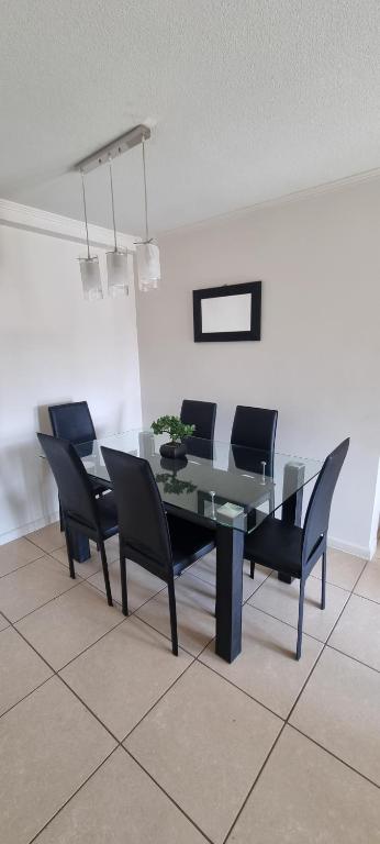 a dining room with a black table and chairs at Departamento por Dia en Condominio in Arica