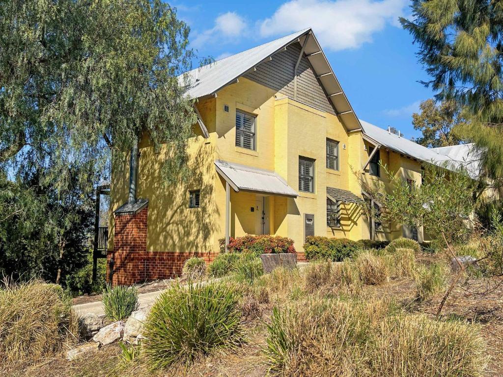 a yellow house with a tree in front of it at Villa AlaBet in Pokolbin