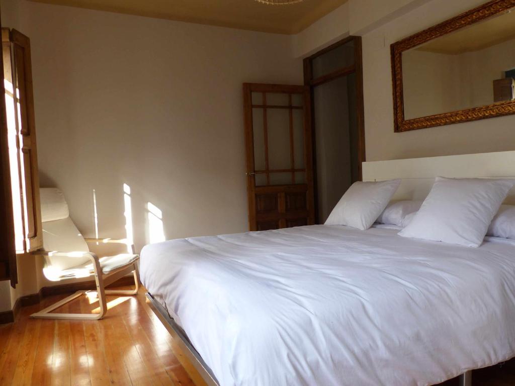 a bedroom with a white bed and a mirror at Apartamento Ábside de San Juan II in Estella