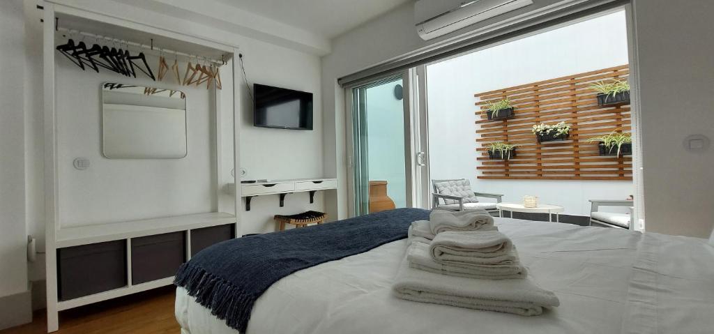 Un dormitorio con una cama y una ventana grande. en Angra Heritage - City Center Hostel, en Angra do Heroísmo