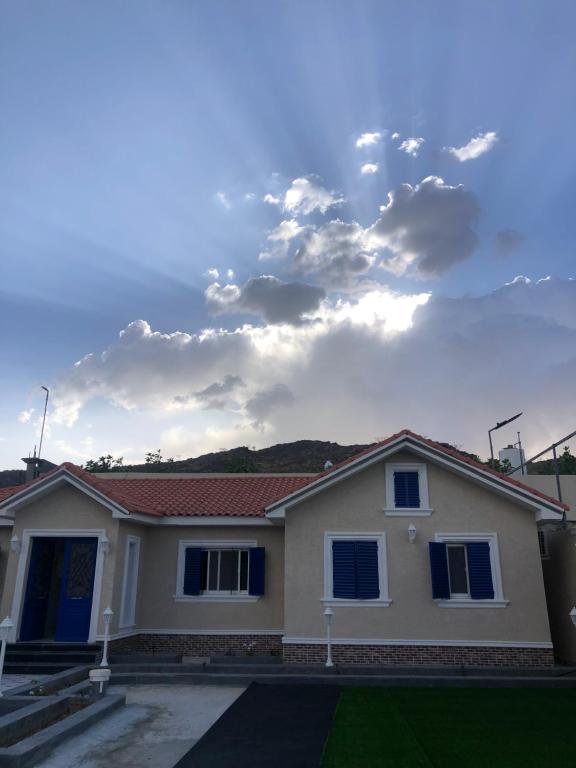 a house with a cloudy sky in the background at شاليه القمر في بهر in Ar Rawḑah