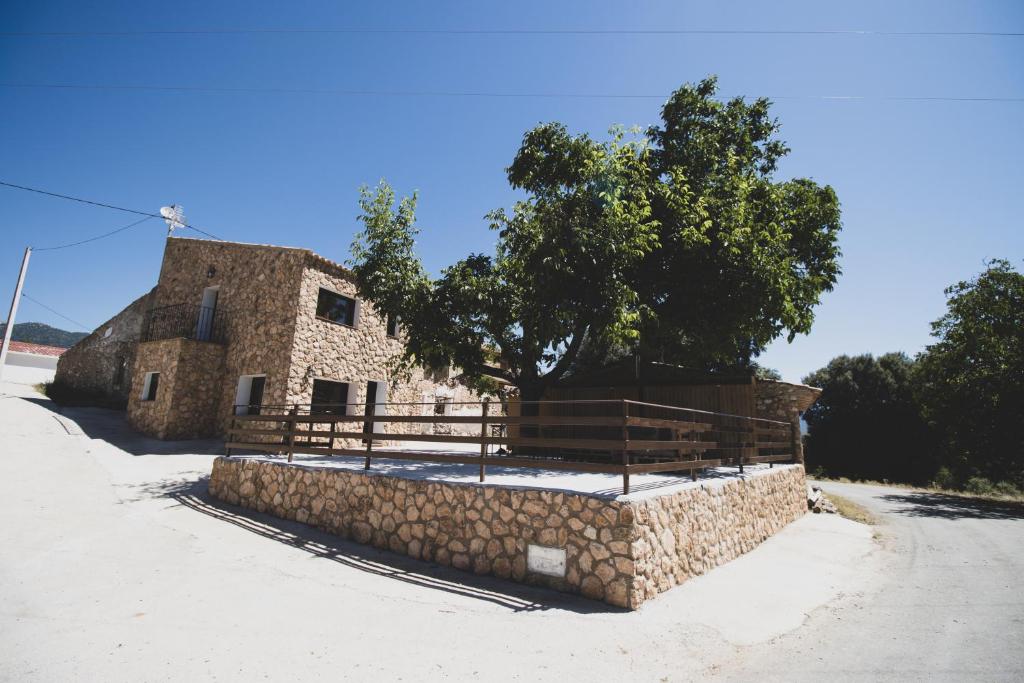 un vecchio edificio in pietra con un recinto e un albero di CASA RURAL EL PADRONCILLO a Riópar