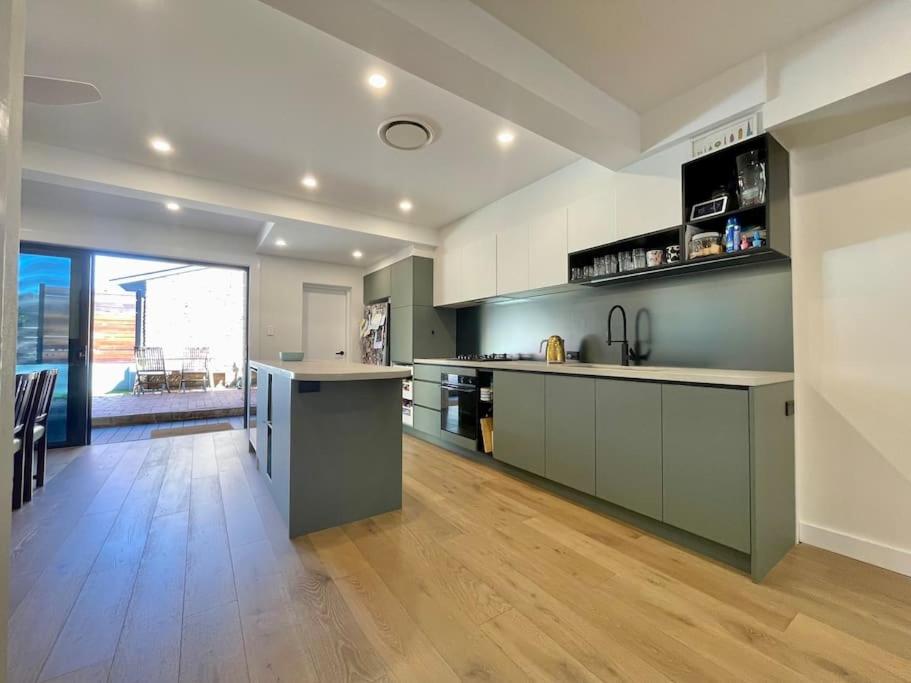 a large kitchen with green cabinets and a wooden floor at DRUM8- 3 Bed townhouse Drummoyne in Sydney