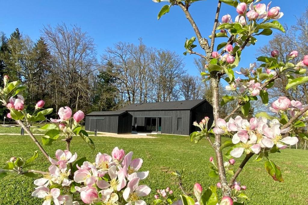 um celeiro preto num campo com flores cor-de-rosa em Le Cottage proche du Golf em Panazol