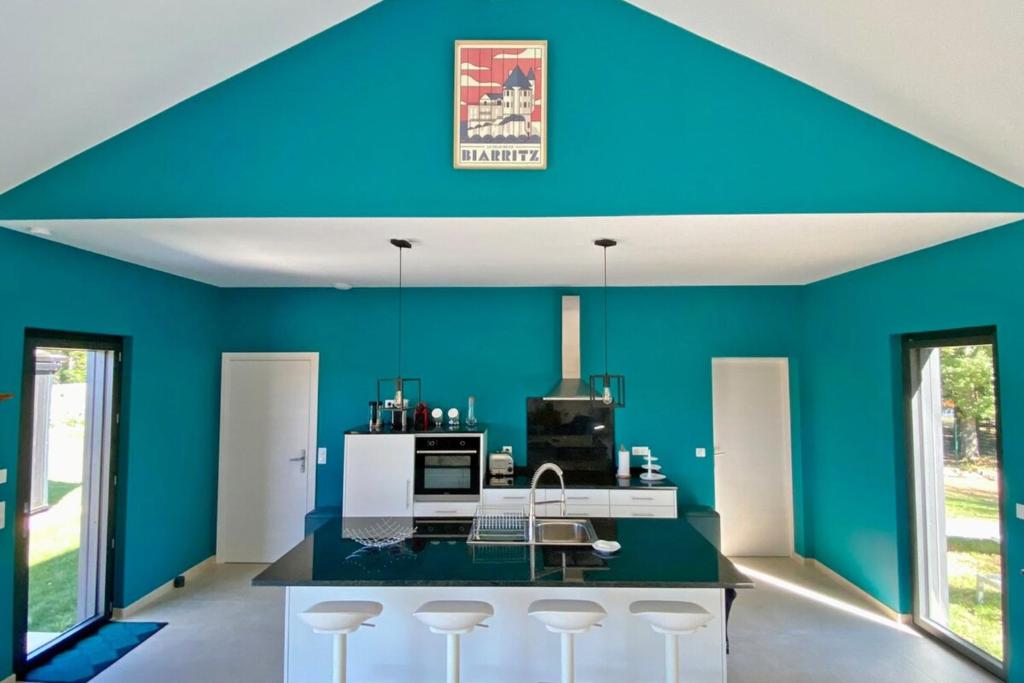 a kitchen with blue walls and a counter with stools at Le Cottage proche du Golf in Panazol