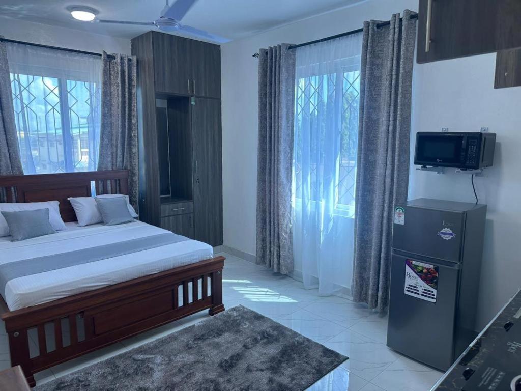 1 dormitorio con 1 cama, TV y ventanas en Grey Pearl Apartments Where Raha is Also Our Priority, en Malindi
