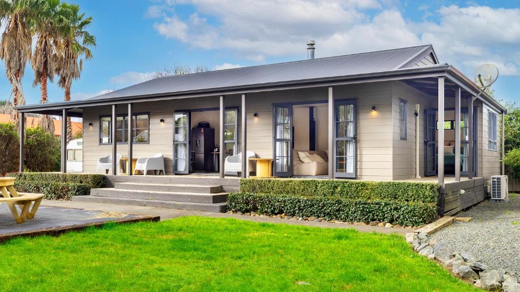 a white house with a porch and a lawn at Matakana Village Central - Modern Holiday Home in Matakana