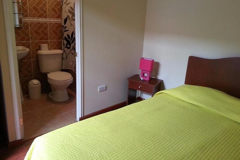 - une chambre avec un lit vert et une boîte rose sur une table dans l'établissement Andina Hostel, à Iquique