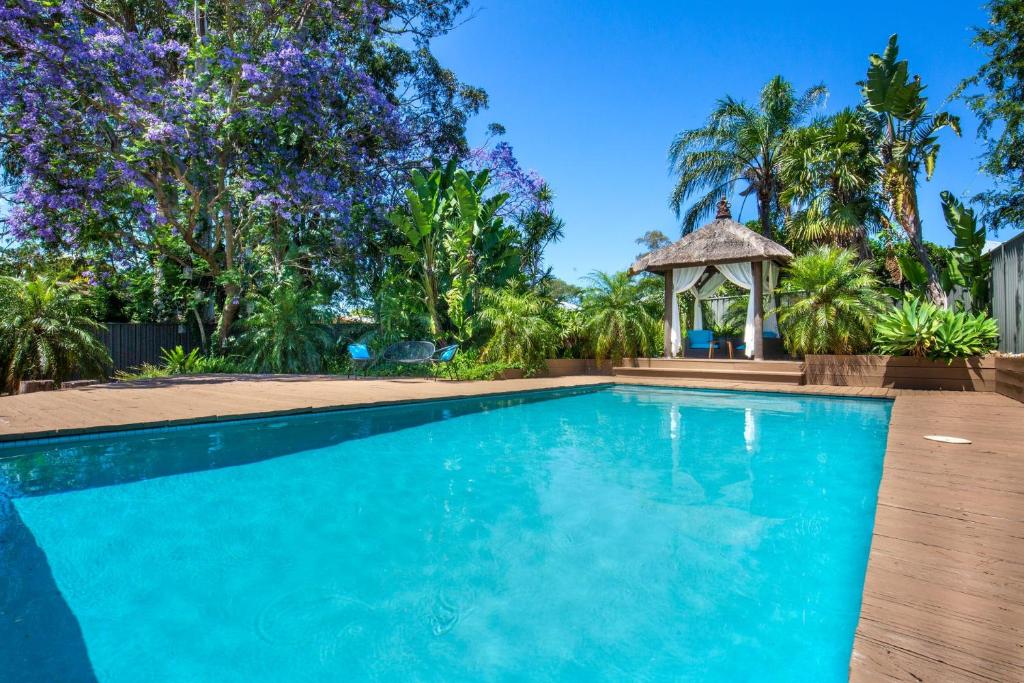 a swimming pool with a gazebo and trees at Bali Huts in Nowra
