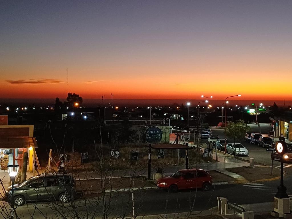 una puesta de sol sobre un aparcamiento con coches aparcados en Departamento en Ciudad De La Punta en La Punta