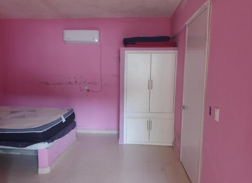 a pink room with a bed and a cabinet at Departamentos el amigo 