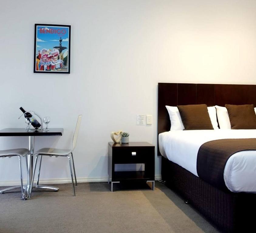1 dormitorio con cama, mesa y escritorio en Golden Reef Motor Inn, en Bendigo