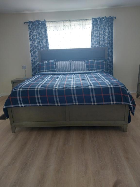 ein Schlafzimmer mit einem Bett mit einer karierten Decke und einem Fenster in der Unterkunft Rustic Redlion Home 