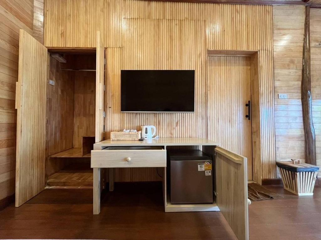 a kitchen with a desk with a tv on a wall at Palm Leaf Resort Koh Tao in Ko Tao
