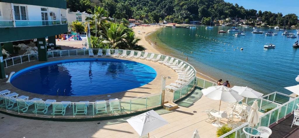 a swimming pool next to a beach and a body of water at Angra inn, Angra dos Reis in Angra dos Reis