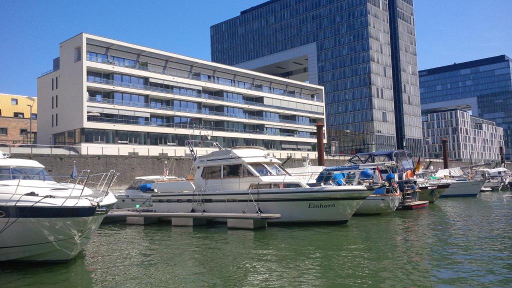 eine Gruppe von Booten, die in einem Yachthafen mit einem Gebäude angedockt sind in der Unterkunft Fantasie Boot EINHORN in Köln