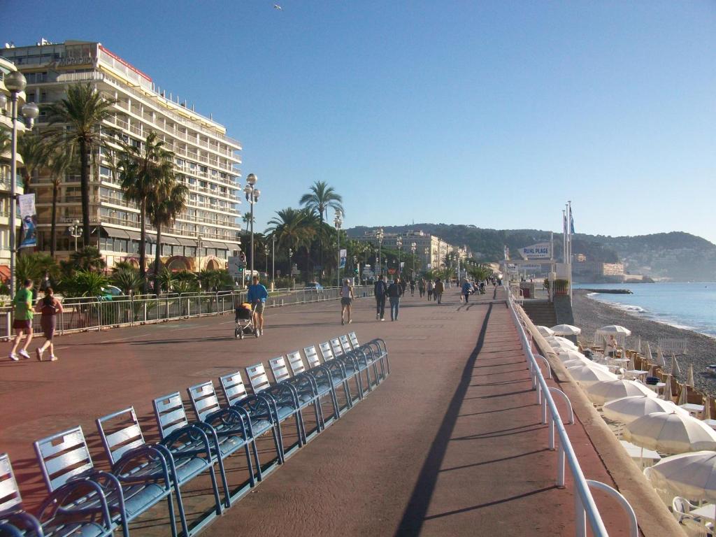 une plage avec des gens et un chien qui marchent sur un trottoir dans l'établissement Appartamento in residence a 50 metri dal mare, à Nice