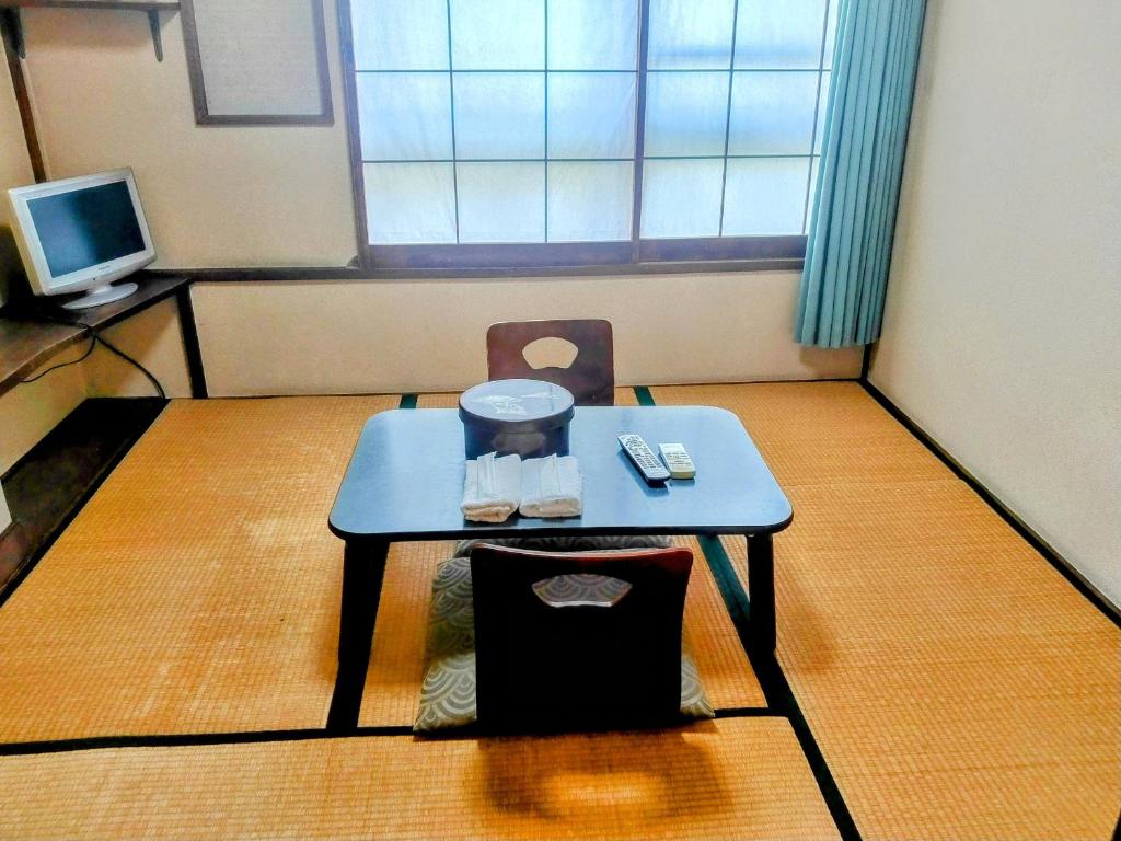 um pequeno quarto com uma mesa e uma televisão em Taiya Ryokan em Fuji