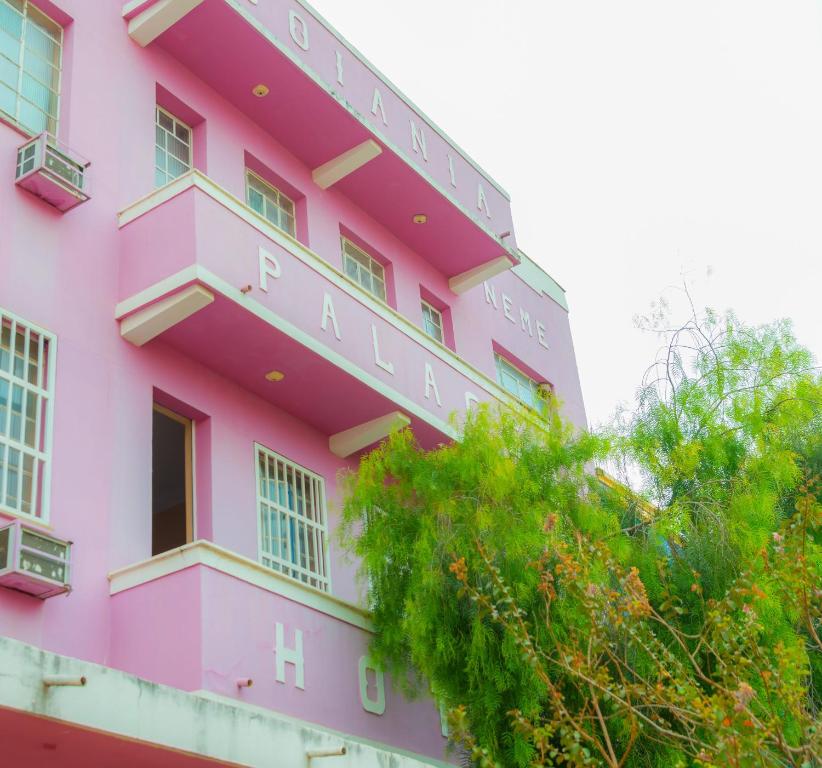 um edifício cor-de-rosa com um cartaz. em Goiânia Palace Hotel em Goiânia