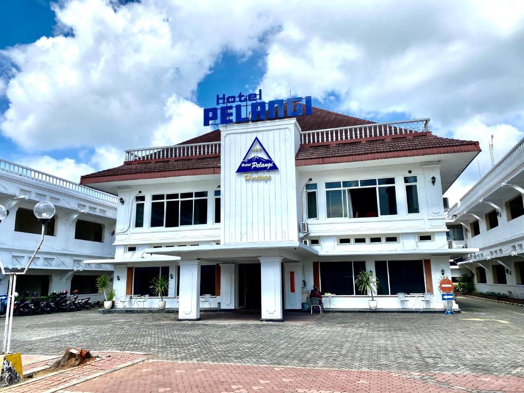 un edificio blanco con una señal azul encima en Hotel Pelangi Malang, Kayutangan Heritage, en Malang