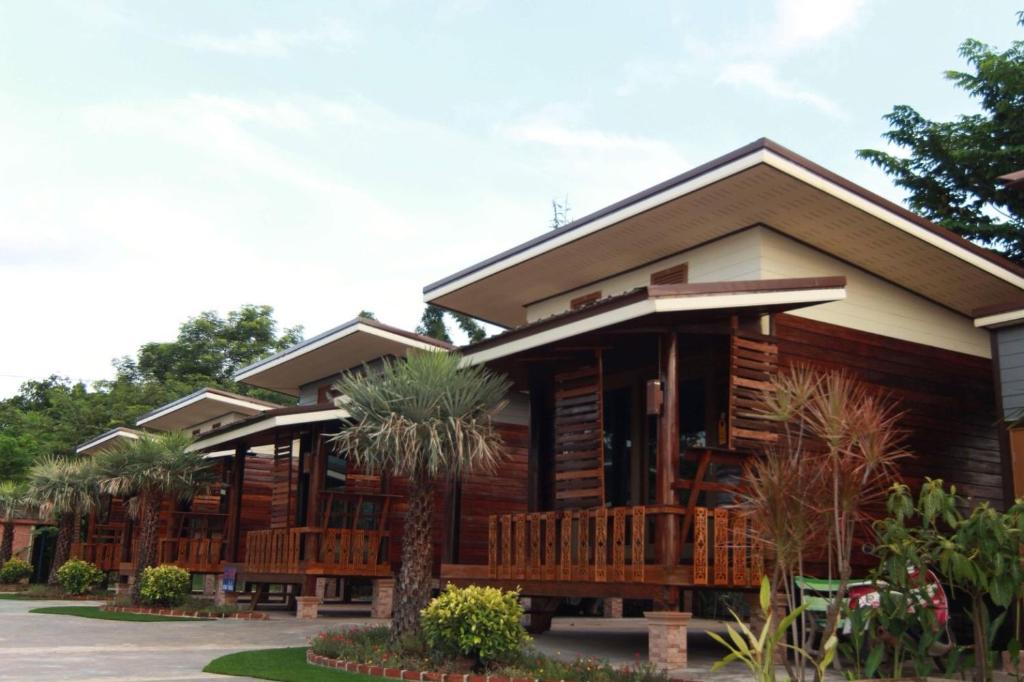 a wooden house with wooden benches in front of it at พบรักรีสอร์ท Pobruk resort in Tha Bo