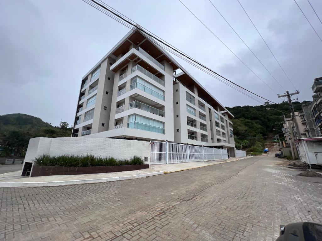 a large white building on the side of a street at Ap. c/ piscina 400m praia in Ubatuba