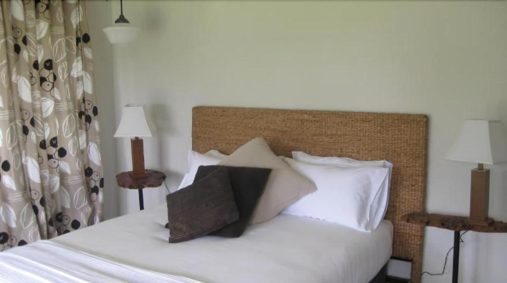 1 dormitorio con 1 cama con sábanas y almohadas blancas en Bodalla Dairy Shed Guest Rooms, en Bodalla