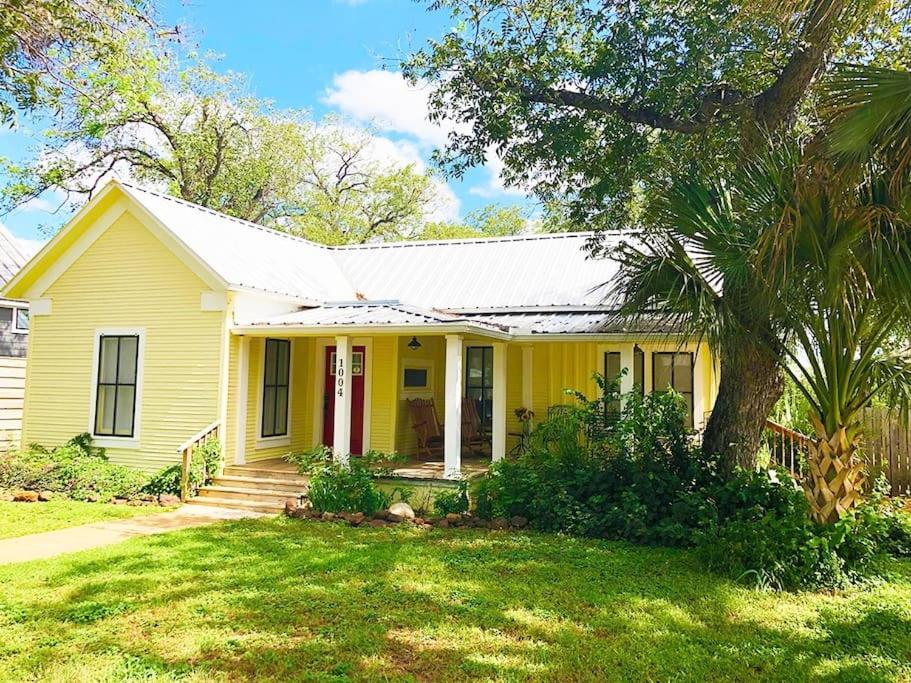 a yellow house with a tree in the yard at Aunt Hattie's Farmhouse in Llano