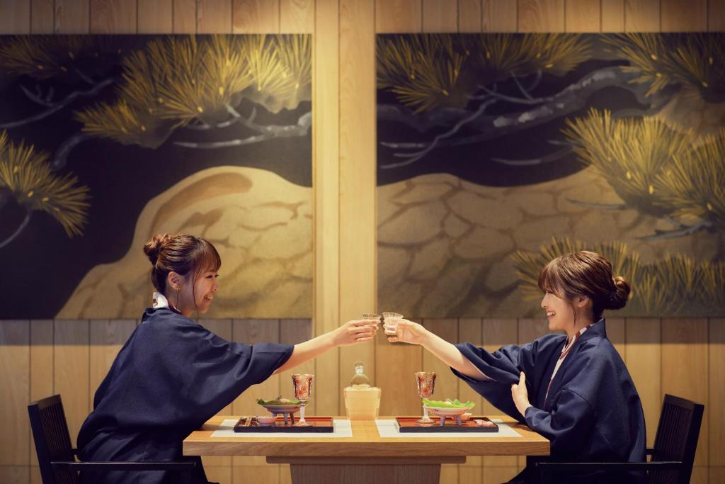 two women sitting at a table shaking hands at Waqoo Naritasanmonzen in Narita