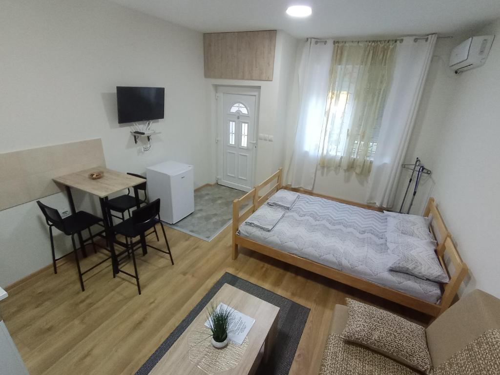 1 dormitorio con cama, escritorio y mesa en BAN apartmani, en Vrbas