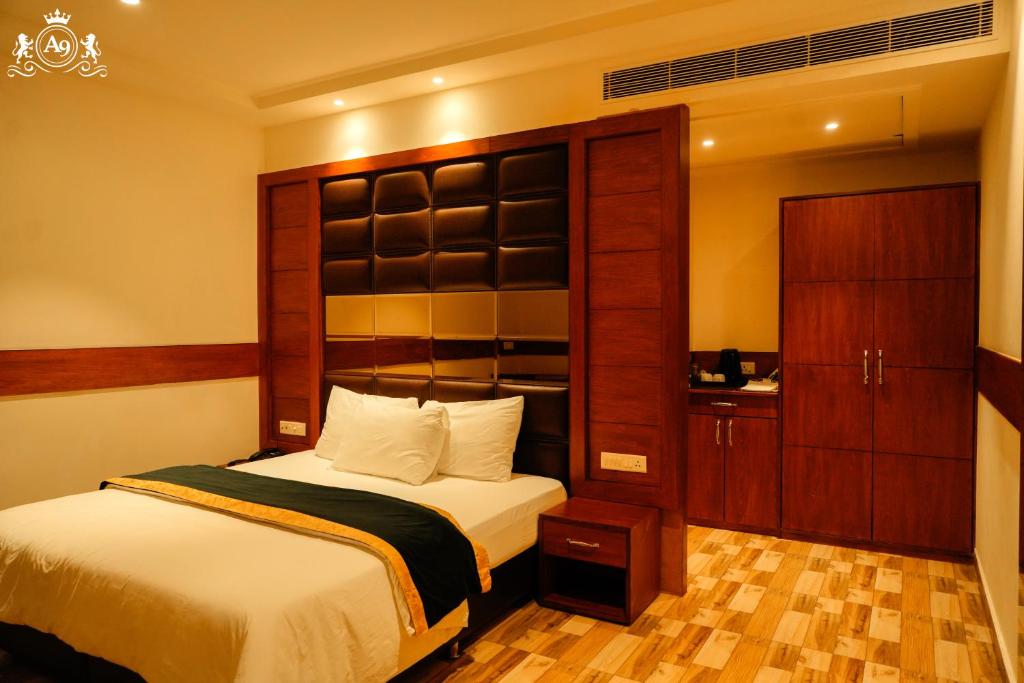 a bedroom with a bed and a wooden cabinet at Hotel A9 Barnala in Barnāla