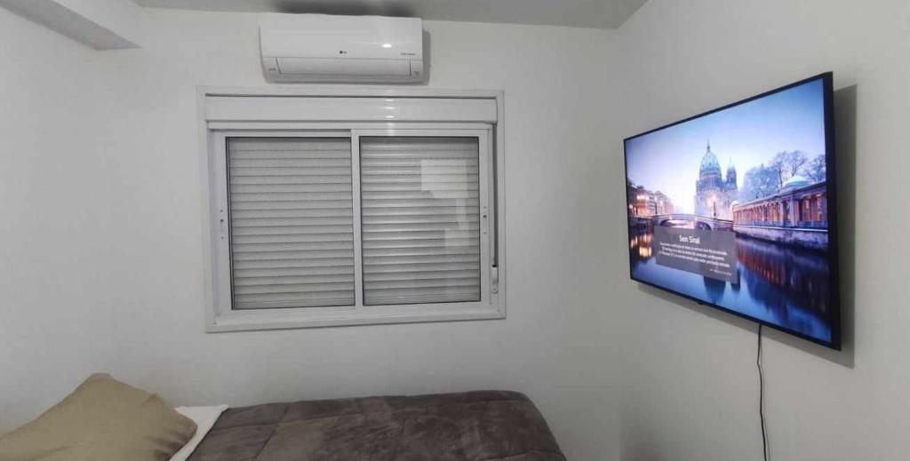 a living room with a window and a flat screen tv at Areatricolor in Porto Alegre