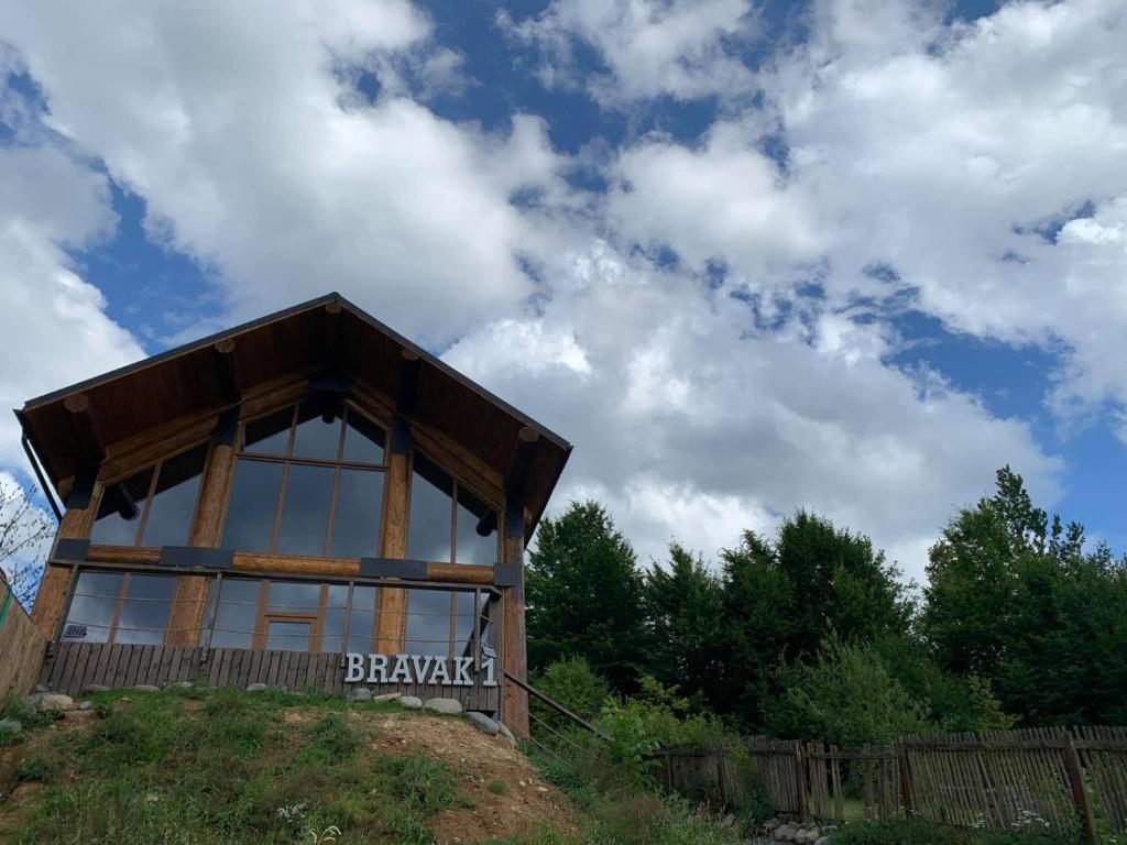 a wooden building with a sign on top of a hill at Cabana Bravak One in Firiza-de-Jos