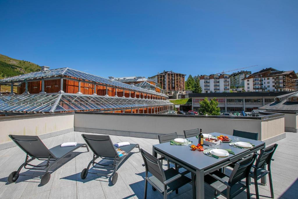 a patio with a table and chairs on a roof at Sestriere Terrace Apt Few Steps From Ski - Happy Rentals in Sestriere