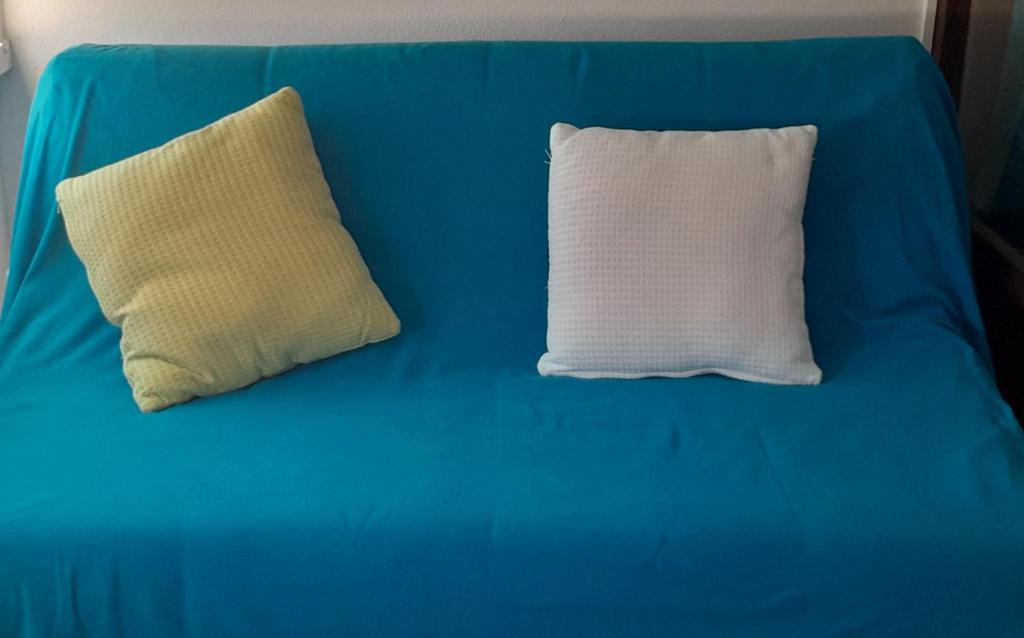 a blue couch with a white pillow on it at Small apartment by the beach in Sesimbra