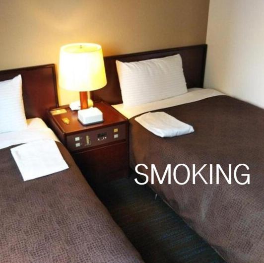 two beds in a hotel room with the words smokeling at Select Inn Hamamatsu Ekimae in Hamamatsu