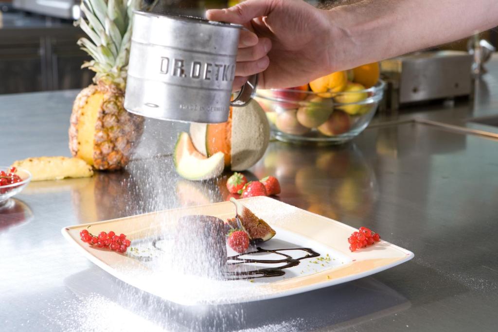 a person is holding a cup and a plate of fruit at Hotel Bergland in Pertisau