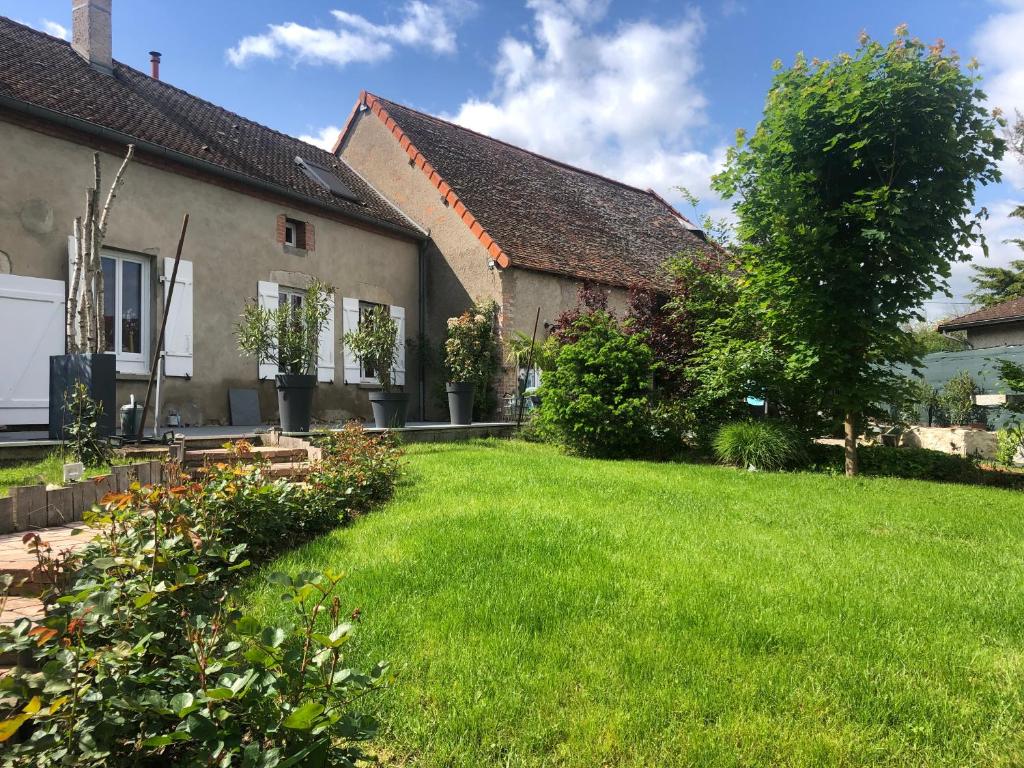 un patio frente a una casa con césped verde en A 10mn de VICHY studio dans ancienne ferme, en Vichy