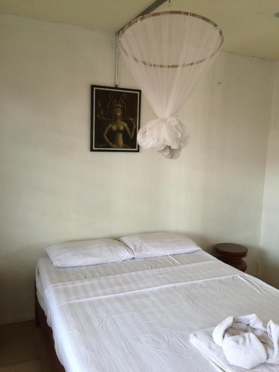 a bedroom with a bed with a picture on the wall at Nomad Guesthouse in Kratie
