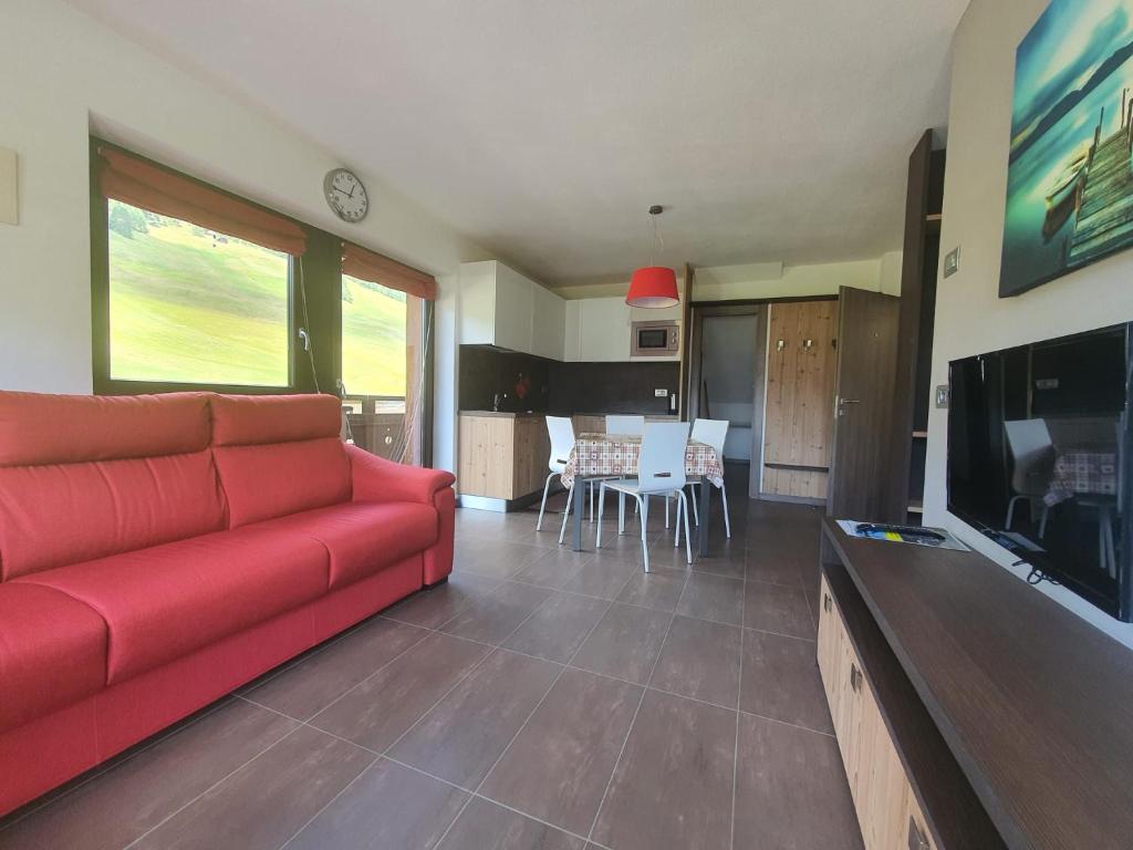 salon z czerwoną kanapą i kuchnią w obiekcie VERDELAGO Appartamenti e CASA CRY w Livigno