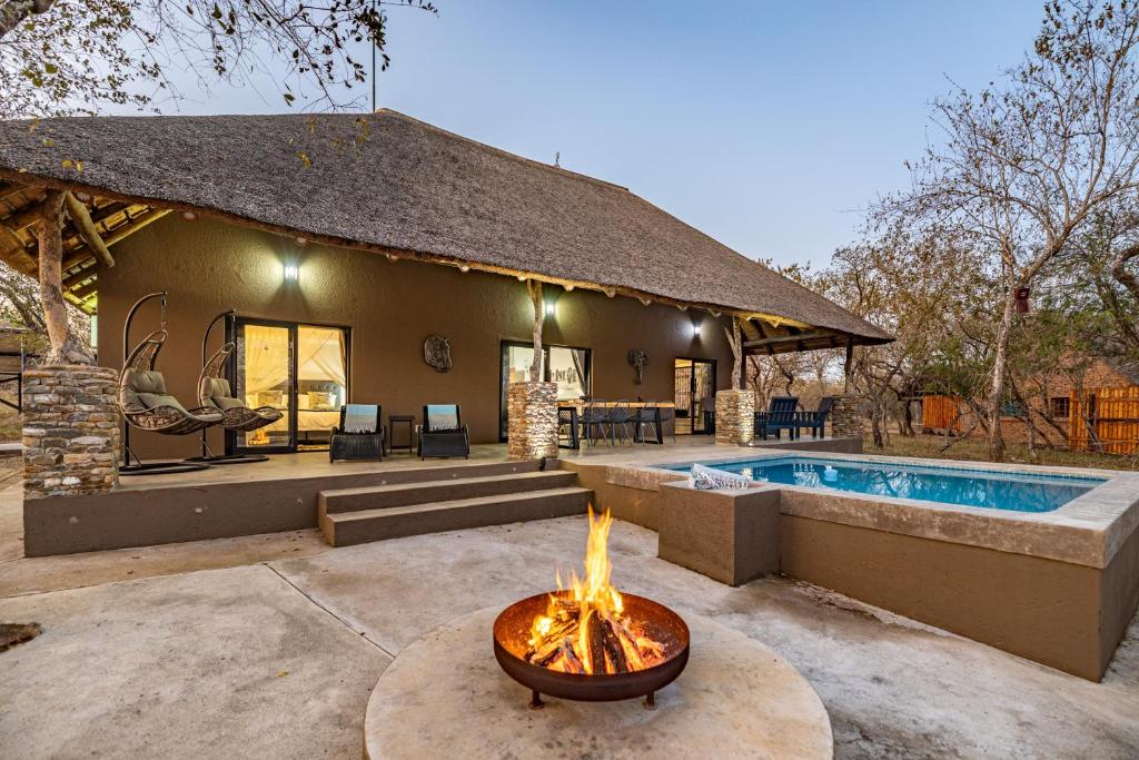 a house with a fire pit next to a pool at Blue Goose Bush Retreat in Marloth Park