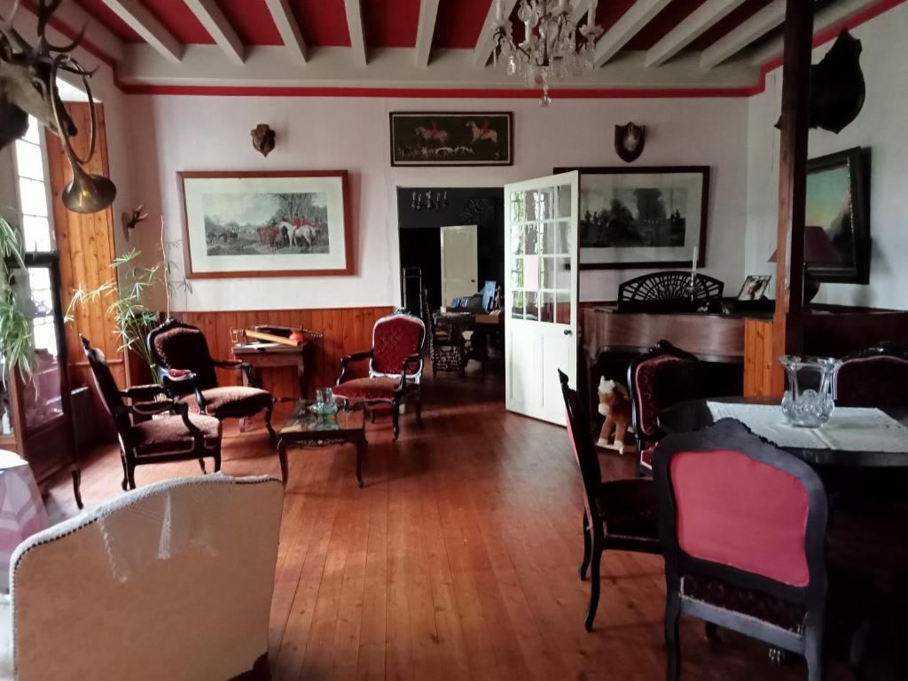 sala de estar con suelo y sillas de madera y mesa en Domaine de Frély, en Pouzauges