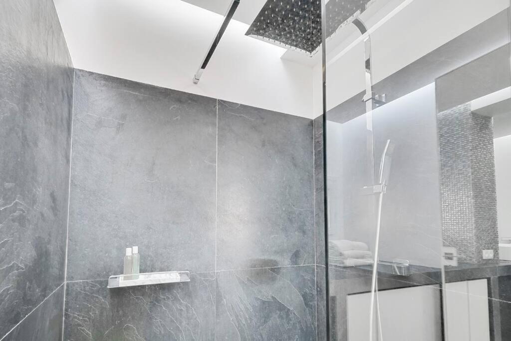 a bathroom with a shower with a glass door at Luxury modern two bedroom duplex by Roland Garros in Paris