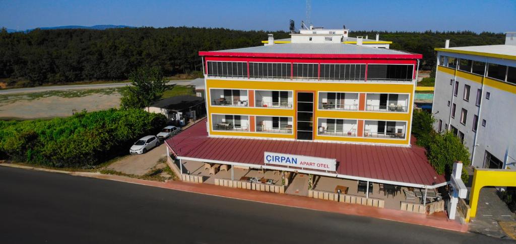 un edificio amarillo con techo rojo junto a un aparcamiento en çırpan apart otel, en Enez