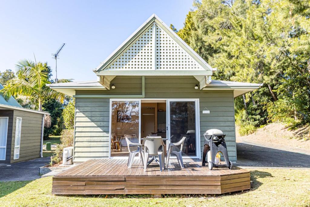 ein Haus mit einer Terrasse mit einem Tisch und Stühlen in der Unterkunft Sea Shell Chalet at Berrara Chalets in Berrara