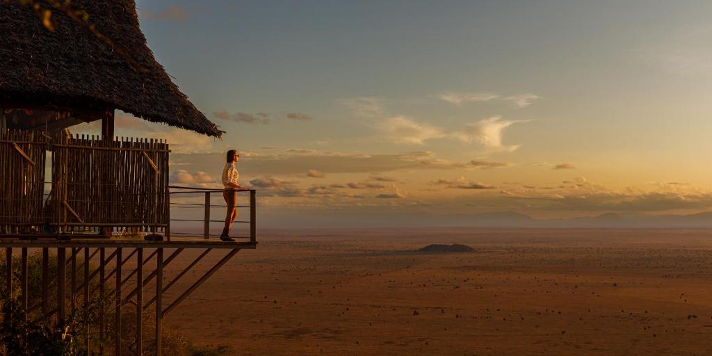 Una mujer parada en una cubierta con vistas al desierto en Soroi Lions Bluff Lodge 