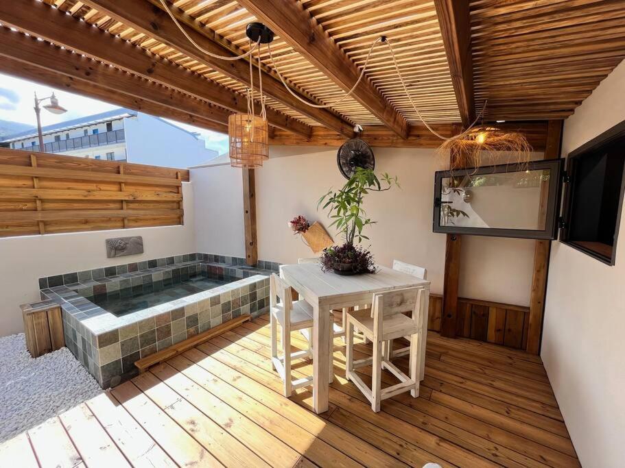 a patio with a hot tub and a table and a television at Ti Kaloo, 2ème ligne, 40 m du Lagon in Saint-Leu