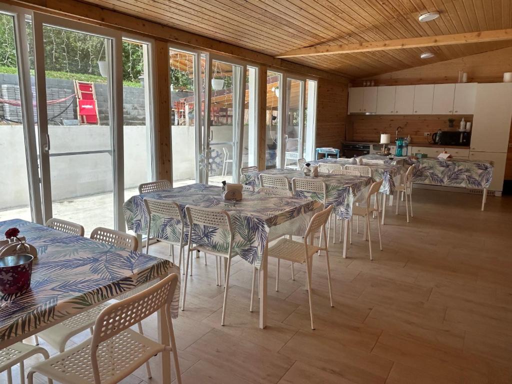 a row of tables and chairs in a room with windows at COMPLEX TURISTIC AVENTURA CAMP in Eşelniţa